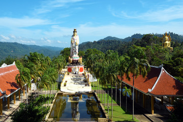Wall Mural - panorama view to Wat Bang Riang temple in the jungle of Phang Nga province Thailand, with giant seated golden Buddha and large statue of Kwam Im (Guan Yin), the Chinese Goddess of Mercy
