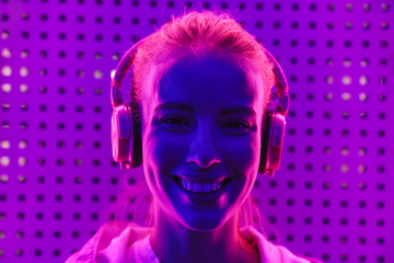 Poster - Image of woman listening to music with headphones over neon illumination