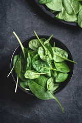 Wall Mural - Fresh spinach leaves in the blacl blowl on a dark textured background