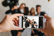 © Look! - Blur indoor portrait of ecstatic young people with balloons having fun at home party with smartphone on foreground. European man making photo of relatives during event using phone.