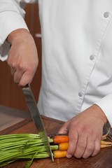 Canvas Print - Male Chef Cutting Carrots On Wooden Board