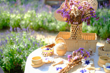 Purple Flower, Candle, Wicker Basket Decorating On Table In Garden