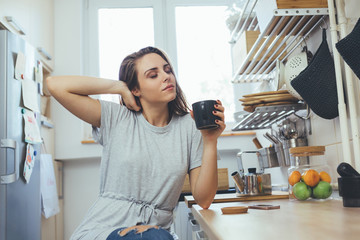 Wall Mural - young woman drinking morning coffee in her kitchen