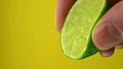 Wall Mural - man squeezes lime on a yellow background