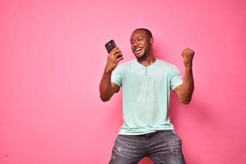 handsome excited young black man feeling excited while viewing content on his smartphone, celebrating winning