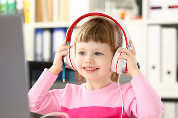 little girl wearing headphones use mobile computer
