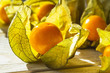 Close-up of yellow ripe physalis fruit (Physalis peruviana) in the sunshine on a white wooden table. Fruits and vegetables, vegetarian and healthy eating. Ready to eat.