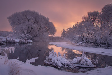 Fototapete - Winter scene at sunrise. Wintry morning with colorful sky on river. Beautiful snowy nature landscape. Amazing winter scenery with reflections in water