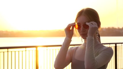 Poster - Beautiful young woman on waterfront at sunset. Space for text