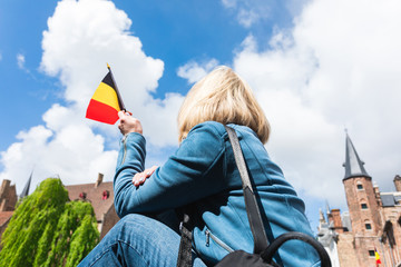 Wall Mural - A young woman with the flag of Belgium in her hands is enjoying the view of the canals in the historical center of Bruges.