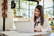 © chika_milan - Attractive businesswoman sitting in cafe and using laptop. On table are laptop, notebook and cup of coffee. Hands are on keyboard.