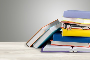 Wall Mural - stack of books and eyeglasses on wooden background