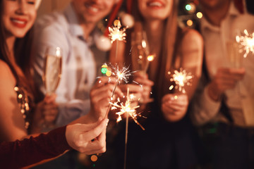 friends with sparklers celebrating new year at party