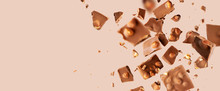 Flying In The Air Broken Bar Of Milk Chocolate With Nuts And Flakes On Pastel Pink Background.  Chocolate Pieces Levitation Concept. Wide Banner.