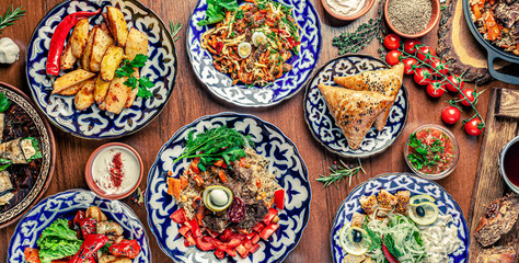 Traditional Uzbek oriental cuisine. Uzbek family table from different dishes for the New Year holiday. The background image is a top view.