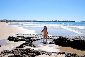 Wall Mural - A baby girl admiring the ocean view and sun reflection on the water, Sydney, Australia