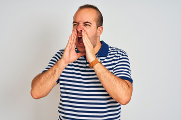 Sticker - Young man wearing casual striped polo standing over isolated white background Shouting angry out loud with hands over mouth