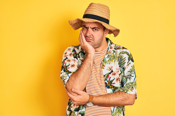 Poster - Young man on vacation wearing summer shirt and hat over isolated yellow background thinking looking tired and bored with depression problems with crossed arms.