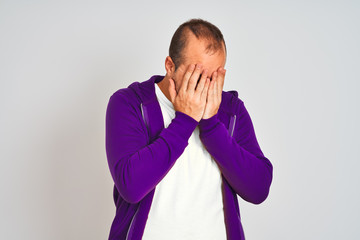 Sticker - Young man wearing purple sweatshirt standing over isolated white background with sad expression covering face with hands while crying. Depression concept.