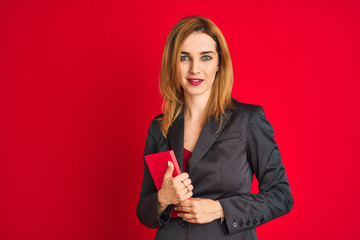 Young beautiful redhead businesswoman wearing suit holding book