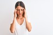 © Krakenimages.com - Beautiful redhead woman wearing casual white t-shirt over isolated background with hand on head for pain in head because stress. Suffering migraine.