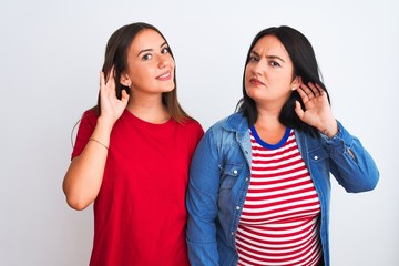 Poster - Young beautiful women wearing casual clothes standing over isolated white background smiling with hand over ear listening an hearing to rumor or gossip. Deafness concept.