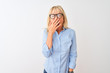 © Krakenimages.com - Middle age businesswoman wearing elegant shirt and glasses over isolated white background bored yawning tired covering mouth with hand. Restless and sleepiness.