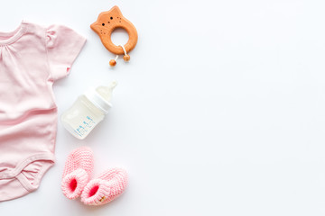 Wall Mural - Newborn girl set - clothes as bodysuit, booties, toys - on white table top-down frame copy space