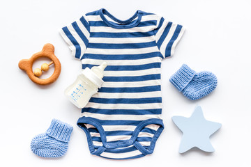 Blue bodysuit for baby boy near children's accessories on white background top-down