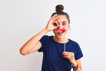 Canvas Print - Young beautiful woman holding fanny party mustache over isolated white background with happy face smiling doing ok sign with hand on eye looking through fingers