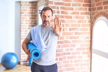 Middle Age Handsome Sportman Holding Mat And Towel Standing Before Do Exercise At Gym With Open Hand Doing Stop Sign With Serious And Confident Expression, Defense Gesture
