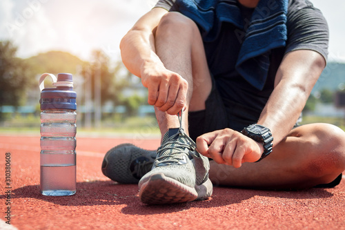 Man runner tying shoelaces on track stadium. Poster Mural XXL