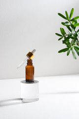 Wall Mural - Serum or essential oil bottle isolated on with background with green leaves. Beauty product concept.