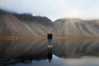 © Johnér - Woman standing on water with mountains reflected in it