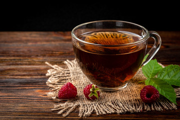 Wall Mural - Cup of black tea and raspberry on dark wooden background.