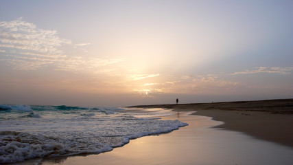 Canvas Print - person enjoying an evening walk on a secluded tropical beach in Cape Verde at sunset