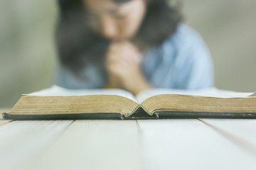 Poster - Young woman are praying and hold clay earth in hands with the open bible,prayer for the world concept