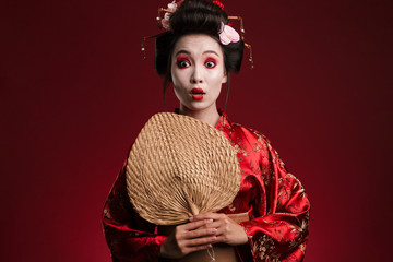 Poster - Image of young geisha woman in japanese kimono holding wooden hand fan