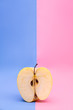 half an apple on a pink and blue background