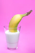 banana in a glass of milk on a pink background