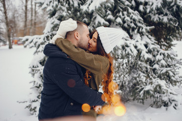 Pretty couple walking in a winter park. Man and woman have fun with snow