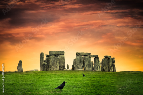 Fotografía Historic Stonehenge under colorful sunset with black crows