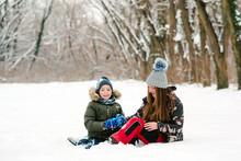 Happy Christmas Vacation. Young Mother And Son Having Fun In Winter Park. Family Playing With Snow Outdoors