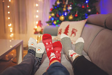 Four Pair Of Feet In Christmas Socks, Mom And Children Lying On The Couch, Enjoying Christmas Time
