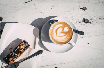 Top view of cappuccino and snack on white table