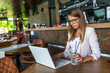 © Dragana Gordic - Smiling woman sitting in cafeteria holding coffee mug and working on laptop. Businesswoman checking email on laptop. Beautiful middle aged woman and using laptop at cafe while drinking a cup of tea.