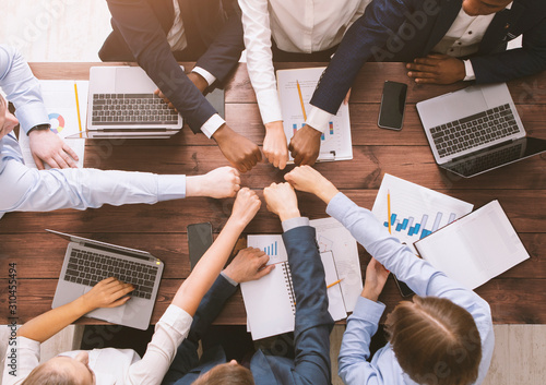 Fotografía Fist bump of corporate team at meeting in office, top view