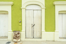 Traditional House Wooden White Door With Rusty Long Chain Lock Hanging On Green Color Cement Wall Colonial Style In Mexico