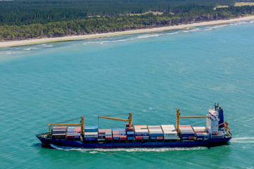 Picture of a cargo ship passing small strait near Tauranga city