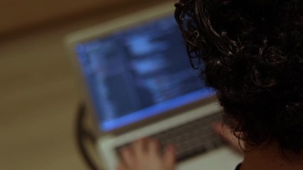 View from the back of man writing program code on laptop close up. Developer of software